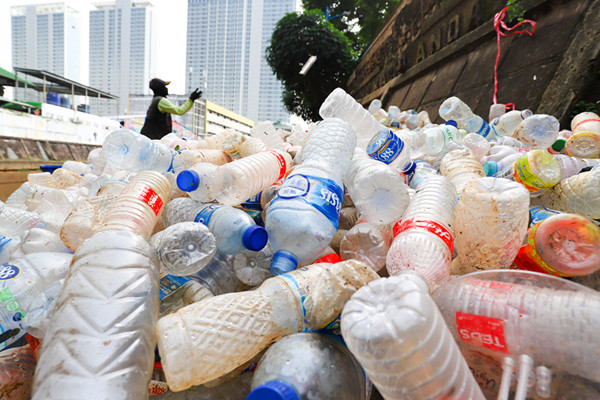 Petugas mengangkut sampah botol plastik dari kali Ciliwung, Jakarta Pusat, Kamis (10/6/2021).