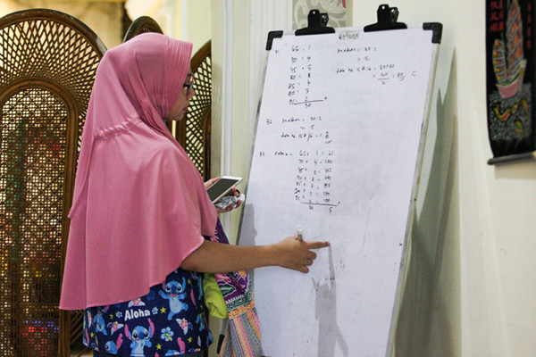 Seorang anak sedang belajar mengerjakan soal dari sekolah dibantu pengajar bimbingan belajar (bimbel) di kawasan Condet, Jakarta Timur, Jumat (11/6/2021).
