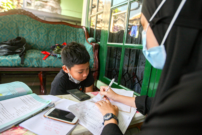 Seorang anak sedang belajar mengerjakan soal dari sekolah dibantu pengajar bimbingan belajar (bimbel) di kawasan Condet, Jakarta Timur, Jumat (11/6/2021).