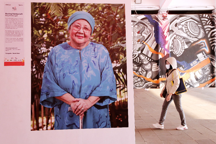 Pejalan kaki melintas di dekat pameran foto Jakpreneur Fest di Terowongan Kendal, Jakarta, Jumat (11/6/2021).