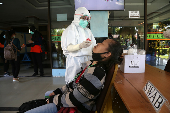 Pekerja Migran Indonesia (PMI) menjalani tes Swab PCR saat tiba di Asrama Haji Sukolilo Surabaya, Jumat (11/6/2021).