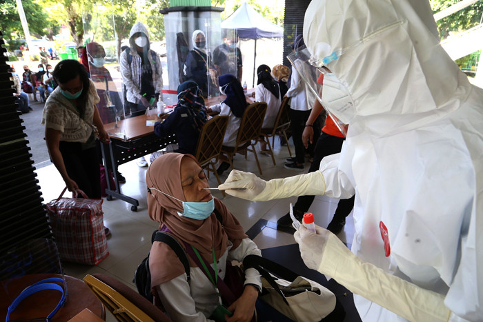 Pekerja Migran Indonesia (PMI) menjalani tes Swab PCR saat tiba di Asrama Haji Sukolilo Surabaya, Jumat (11/6/2021).