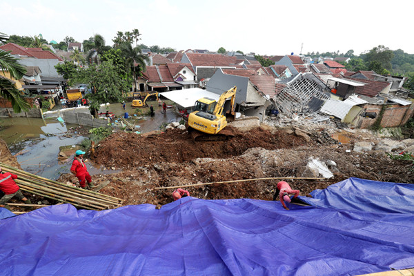 Petugas memasang terpal untuk menutupi tanah longsor di Perumahan Nerada Estate Ciputat, Tangerang Selatan, Banten, Sabtu (12/6/2021).