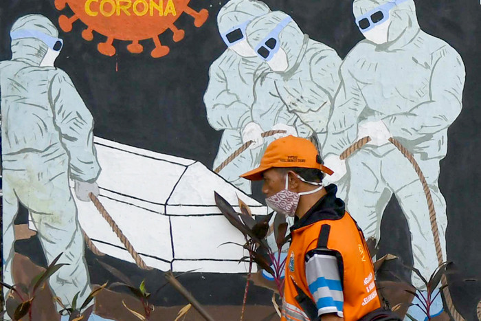 Petugas dan warga saat melintas di depan mural himbauan pandemi Covid-19 di Jakarta Selatan, Selasa (15/6/2021).