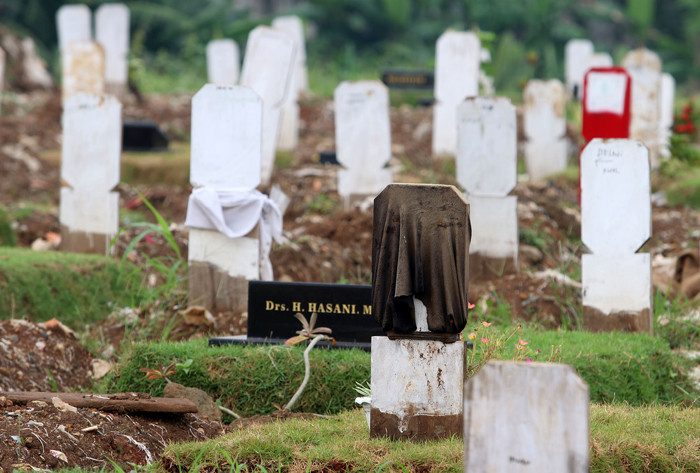 Sebuah papan nisan diberi kain penanda di TPU Srengseng Sawah, Jakarta Selatan, Jumat (18/6/2021).