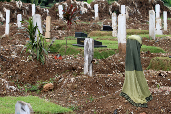 Sebuah papan nisan diberi kain penanda di TPU Srengseng Sawah, Jakarta Selatan, Jumat (18/6/2021).