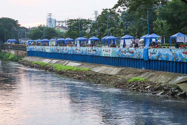 Sejumlah stand bazar ukm dengan berlatar mural cantik bertemakan kehidupan sungai di kawasan Kanal Banjir Barat, Jakarta Pusat, Senin (21/6/2021).
