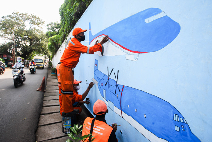 Petugas Penanganan Prasarana dan Sarana Umum (PPSU) menyelesaikan mural di tembok kawasan Halim Perdanakusuma, Jakarta, Rabu (21/6/2021).