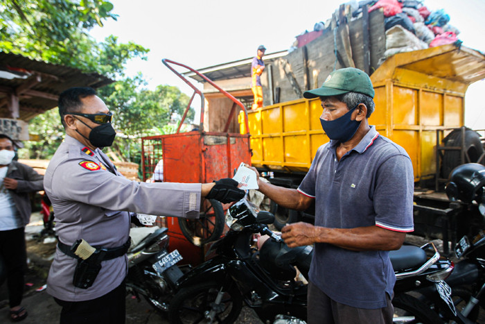Anggota Polsek Cimanggis saat membagikan masker untuk pedagang dan pengunjung di Pasar PAL Cimanggis, Depok, Jawa Barat, Selasa (22/6/2021).