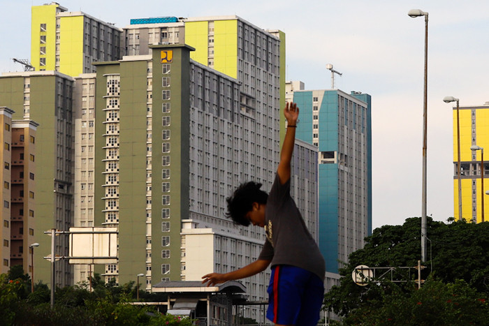 Anak-anak bermain skateboard dengan berlatar belakang gedung Rumah Sakit Darurat Covid-19 (RSDC) Wisma Atlet, Kemayoran, Jakarta Pusat, Selasa (22/6/2021).
