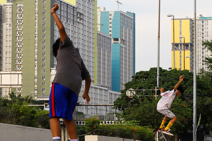 Anak-anak bermain skateboard dengan berlatar belakang gedung Rumah Sakit Darurat Covid-19 (RSDC) Wisma Atlet, Kemayoran, Jakarta Pusat, Selasa (22/6/2021).