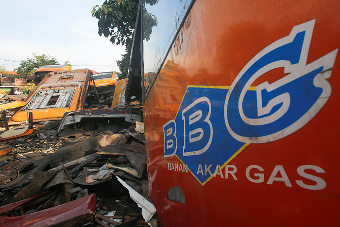 Pejalan kaki melintas di dekat rongsokan bus Transjakarta di Terminal Pulogadung, Jakarta Timur, Minggu (27/6/2021).