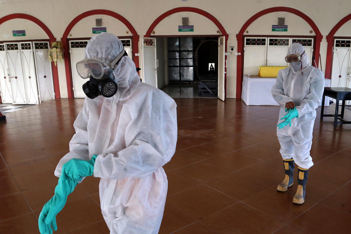 Petugas Krematorium mengenakan Hazmat dan APD memasukkan peti jenazah kedalam tungku pembakaran di Krematorium Keputih, Surabaya, Selasa (29/6/2021).