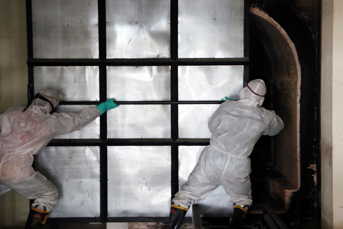 Petugas Krematorium mengenakan Hazmat dan APD memasukkan peti jenazah kedalam tungku pembakaran di Krematorium Keputih, Surabaya, Selasa (29/6/2021).