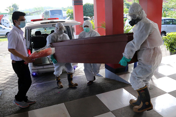 Petugas Krematorium mengenakan Hazmat dan APD memasukkan peti jenazah kedalam tungku pembakaran di Krematorium Keputih, Surabaya, Selasa (29/6/2021).