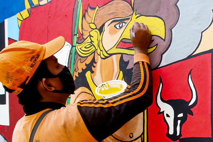 Petugas saat melukis mural ditembok di kawasan Jakarta Pusat, Selasa (29/6/2021).