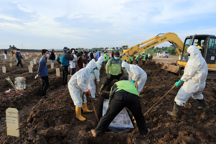 Petugas memakamkan jenazah dengan protokol Covid-19 di TPU Rorotan, Cilincing, Jakarta Utara, Rabu (30/6/2021).