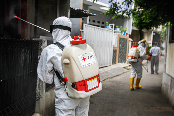 Petugas Palang Merah Indonesia Jaktim saat melakukan penyemprotan cairan disinfektan ke rumah warga di Kelurahan Tengah, Jakarta Timur, Kamis (1/7/2021).