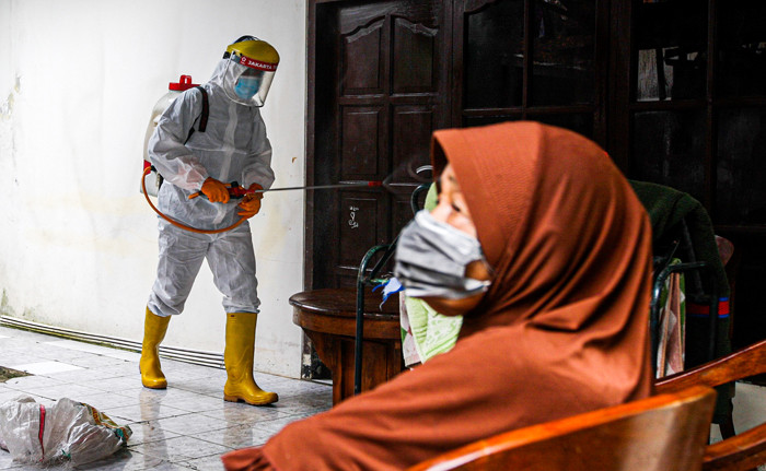 Petugas Palang Merah Indonesia Jaktim saat melakukan penyemprotan cairan disinfektan ke rumah warga di Kelurahan Tengah, Jakarta Timur, Kamis (1/7/2021).