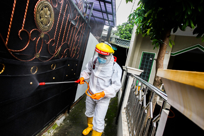 Petugas Palang Merah Indonesia Jaktim saat melakukan penyemprotan cairan disinfektan ke rumah warga di Kelurahan Tengah, Jakarta Timur, Kamis (1/7/2021).