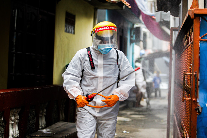 Petugas Palang Merah Indonesia Jaktim saat melakukan penyemprotan cairan disinfektan ke rumah warga di Kelurahan Tengah, Jakarta Timur, Kamis (1/7/2021).