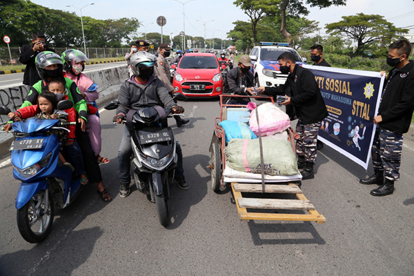 Pembagian masker dan hand sanitizer pada nelayan dan masyarakat di jalur pintu Jembatan Suramadu, Kenjeran Surabaya, Jawa Timur, Jumat (2/7/2021).