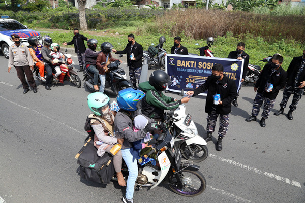 Pembagian masker dan hand sanitizer pada nelayan dan masyarakat di jalur pintu Jembatan Suramadu, Kenjeran Surabaya, Jawa Timur, Jumat (2/7/2021).