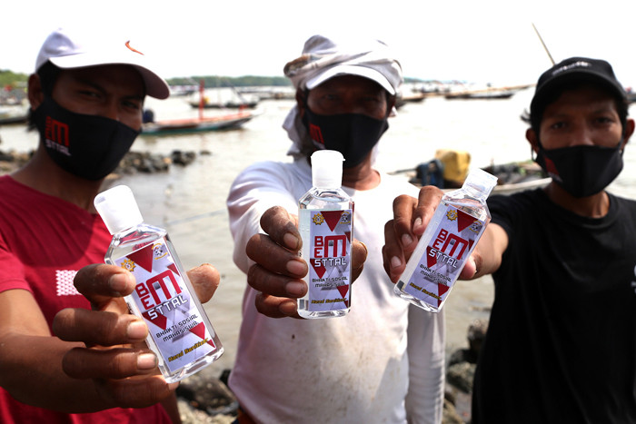 Pembagian masker dan hand sanitizer pada nelayan dan masyarakat di jalur pintu Jembatan Suramadu, Kenjeran Surabaya, Jawa Timur, Jumat (2/7/2021).