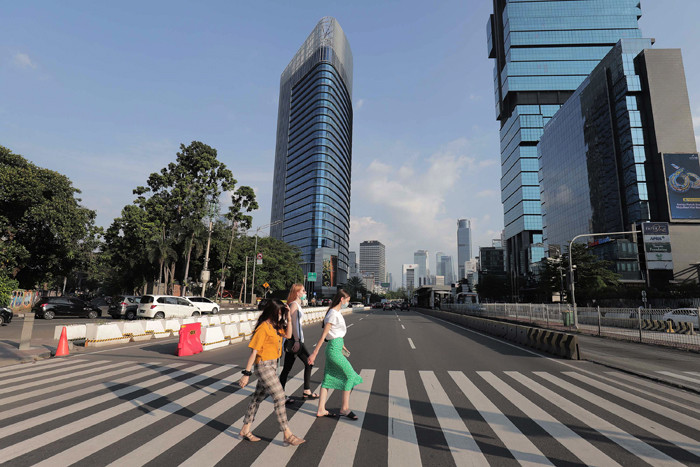 Sejumlah pekerja berjalan di jalur pedestrian Jalan Jenderal Sudirman, Jakarta, Jumat (2/7/2021).