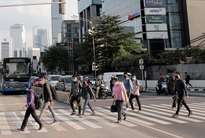 Sejumlah pekerja berjalan di jalur pedestrian Jalan Jenderal Sudirman, Jakarta, Jumat (2/7/2021).