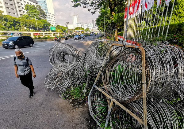 Pejalan kaki saat melintas menghindari kawat pengamanan yang sudah tidak terpakai di kawasan Jalan Gatot Subroto, Jakarta, Jumat (2/7/2021).
