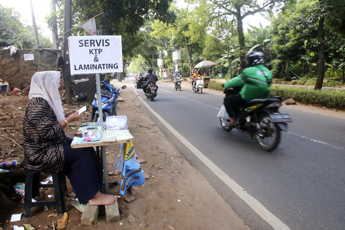 Ade Kalsum (46) tengah memperbaiki KTP elektronik milik warga di Jalan M Kahfi II, Jagakarsa, Jakarta Selatan, Jumat (2/7/2021).