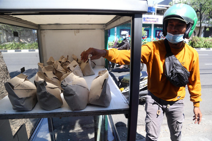 Warga mengambil nasi bungkus gratis didepan salah satu pertokoan di kawasan Jalan Ngagel, Surabaya, Jawa Timur, Minggu (4/7/2021).