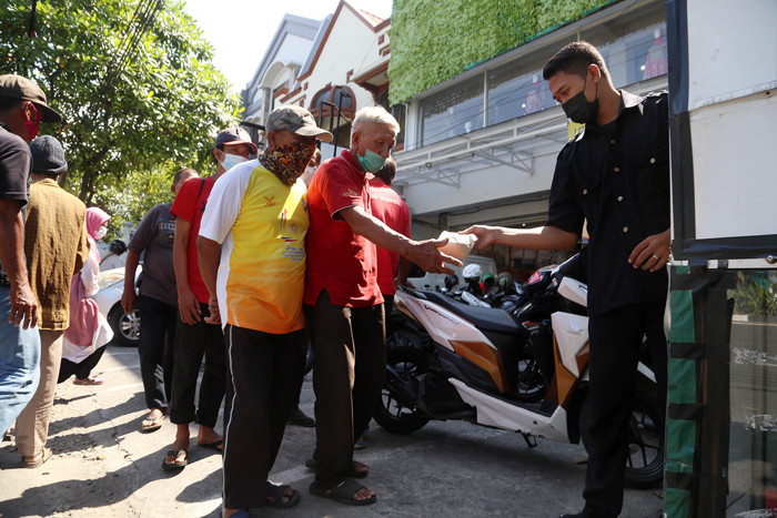 Warga mengambil nasi bungkus gratis didepan salah satu pertokoan di kawasan Jalan Ngagel, Surabaya, Jawa Timur, Minggu (4/7/2021).