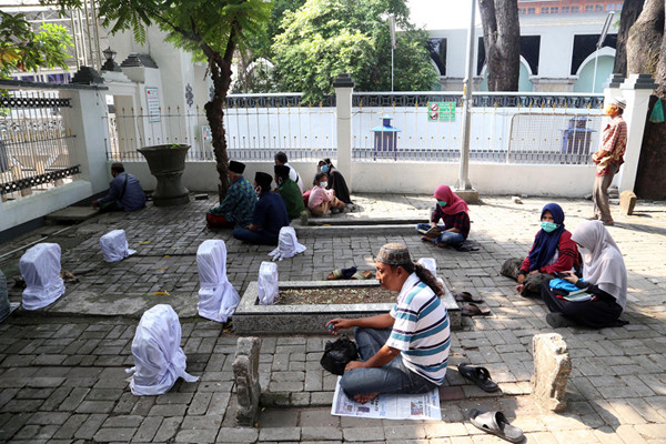 Para peziarah meninggalkan area makam usai berdoa ketika didatangi aparat gabungan di kawasan Makan Sunan Ampel Surabaya, Jawa Timur, Minggu (4/7/2021).