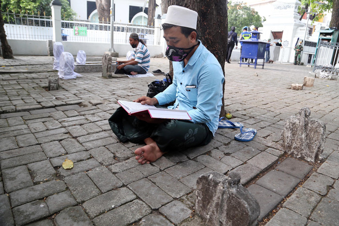 Para peziarah meninggalkan area makam usai berdoa ketika didatangi aparat gabungan di kawasan Makan Sunan Ampel Surabaya, Jawa Timur, Minggu (4/7/2021).