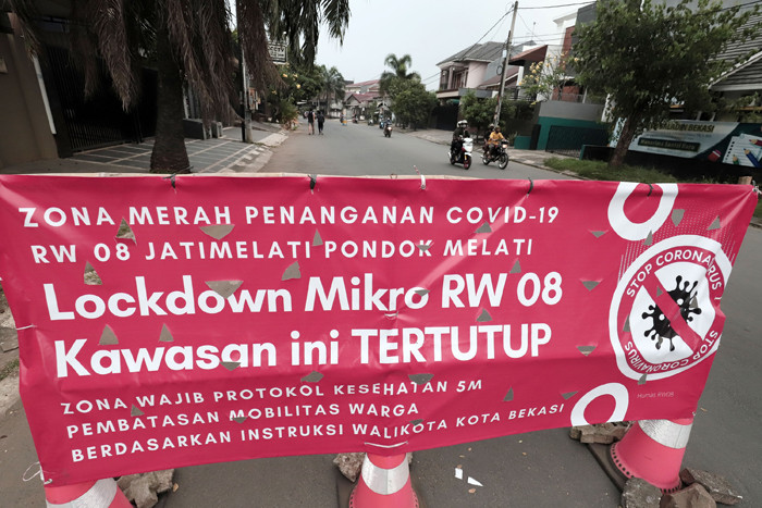 Pengendara melintasi spanduk bertuliskan Lockdown Mikro RW 08 Kawasan Ini Tertutup di kawasan Puri Gading, Kota Bekasi, Jawa Barat, Senin (5/7/2021).