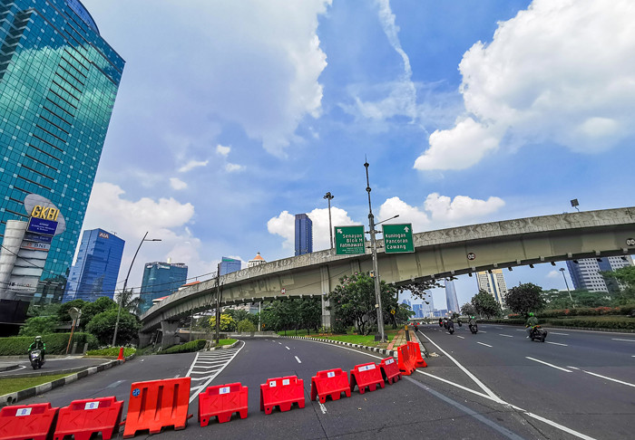 Suasana Jalan Sudirman terlihat lengang pada hari kedua PPKM darurat di Jakarta Pusat, Minggu (4/7/2021).