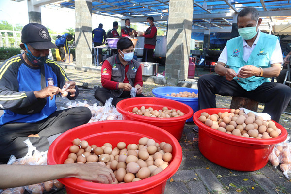Para relawan memasak di dapur umum Kementerian Sosial di area halaman Convention Hall Surabaya, Jawa Timur, Senin (5/7/2021).