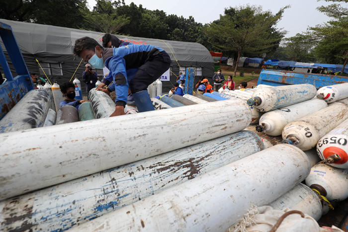 Sejumlah petugas menurunkan tabung berisi oksigen dari truk di Posko Darurat Oksigen Rescue di kawasan Monumen Nasional, Jakarta, Senin (5/7/2021).