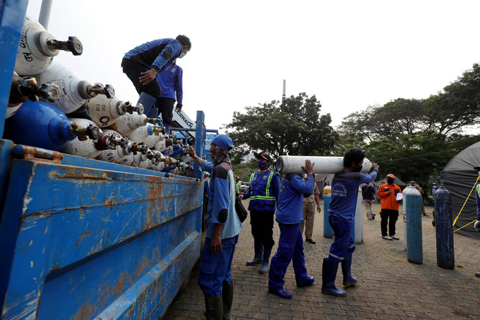 Sejumlah petugas menurunkan tabung berisi oksigen dari truk di Posko Darurat Oksigen Rescue di kawasan Monumen Nasional, Jakarta, Senin (5/7/2021).