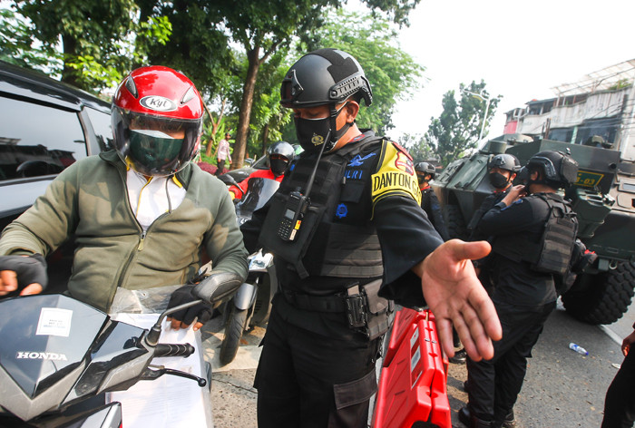 Petugas Brimob saat melakukan pemeriksaan warga yang melewati pos penyekatan PPKM Darurat di Lenteng Agung, Jakarta Selatan, Selasa (6/7/2021).