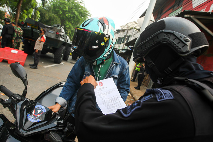 Petugas Brimob saat melakukan pemeriksaan warga yang melewati pos penyekatan PPKM Darurat di Lenteng Agung, Jakarta Selatan, Selasa (6/7/2021).