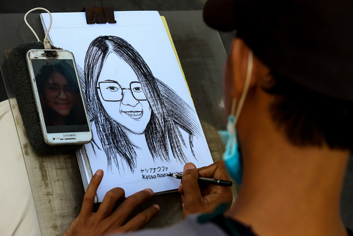 Jasa pembuat sketsa wajah sedang menyelesaikan pesanannya di kawasan Kota Tua, Jakarta Barat, Selasa (6/7/2021).