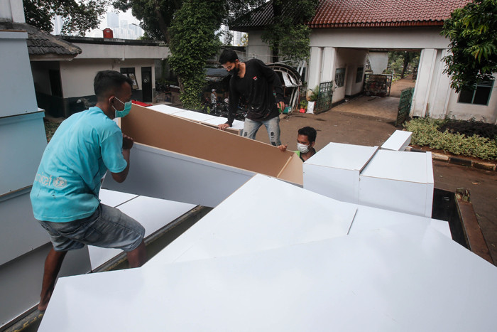 Pekerja mengangkat peti mati untuk dipindahkan ke ambulans di TPU Petamburan, Jakarta Pusat, Selasa (6/7/2021).