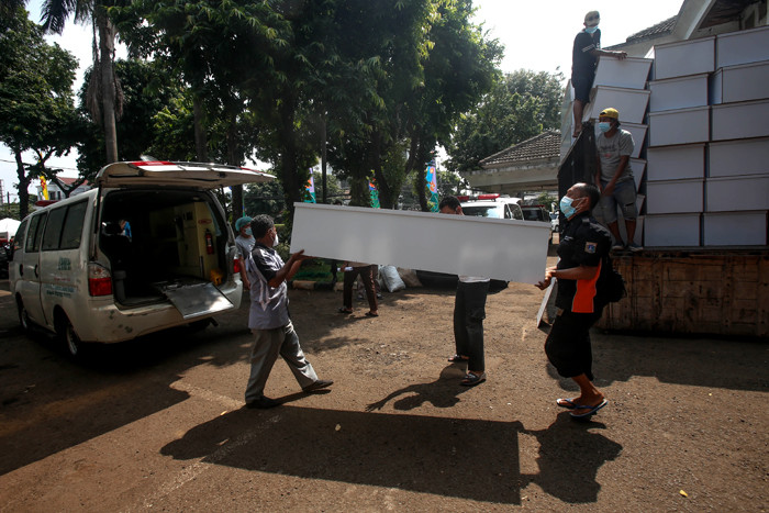 Pekerja mengangkat peti mati untuk dipindahkan ke ambulans di TPU Petamburan, Jakarta Pusat, Selasa (6/7/2021).