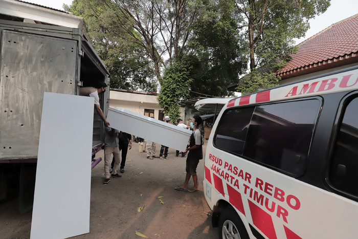 Pekerja mengangkut peti jenazah ke dalam ambulans untuk didistribusikan di TPU Petamburan, Jakarta Pusat, Selasa (6/7/2021).