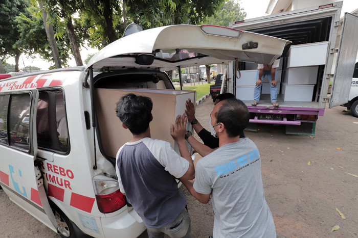 Pekerja mengangkut peti jenazah ke dalam ambulans untuk didistribusikan di TPU Petamburan, Jakarta Pusat, Selasa (6/7/2021).