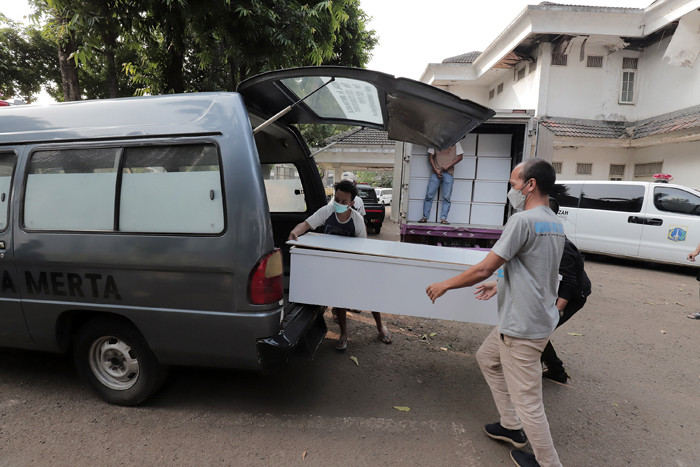 Pekerja mengangkut peti jenazah ke dalam ambulans untuk didistribusikan di TPU Petamburan, Jakarta Pusat, Selasa (6/7/2021).