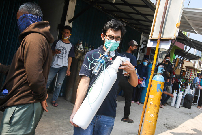 Karyawan toko saat memberikan arahan kepada warga yang akan mengisi ulang tabung oksigen di kawasan Manggarai, Jakarta Selatan, Selasa (6/7/2021).